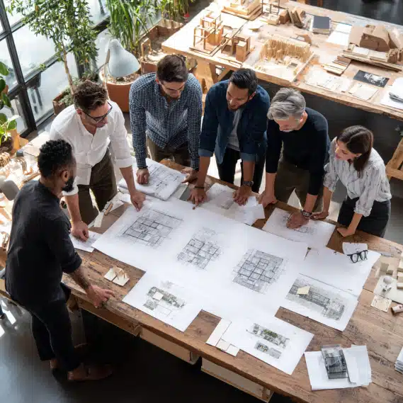 Diverse team of builders and remodelers examining a commercial building blueprint at a modern table.